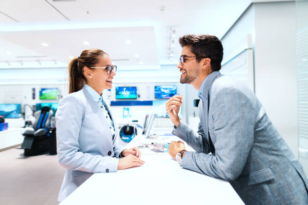 istock Beautiful multicultural couple in suits discussing what to buy. Tech store interior. 1081443628