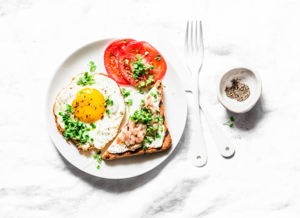 istock Breakfast served - fried egg, smoked mackerel cream cheese toast, tomatoes on a light background, top view 1081445972