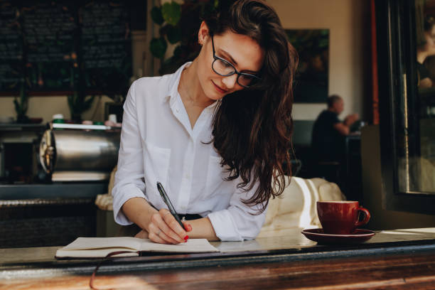 istock Woman writing in book at coffee shop 1081445986