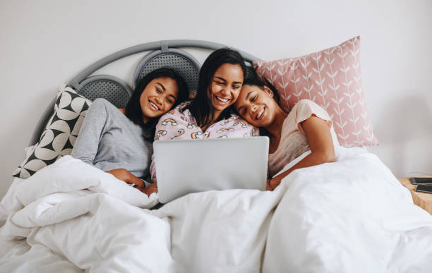 istock Three girls lying on bed looking at a laptop 1081448058