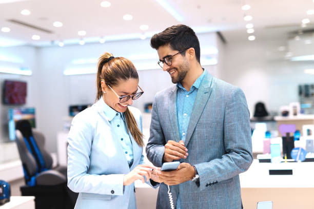 istock Cute multicultural couple dressed in a suit choosing smart phone. Tech store interior. 1081448458