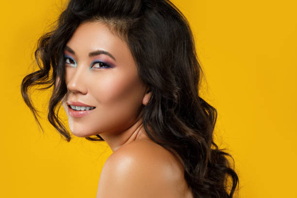 asian woman with a beautiful curly hair and make-up on yellow background - asian ethnicity fashion model beautiful luxury imagens e fotografias de stock