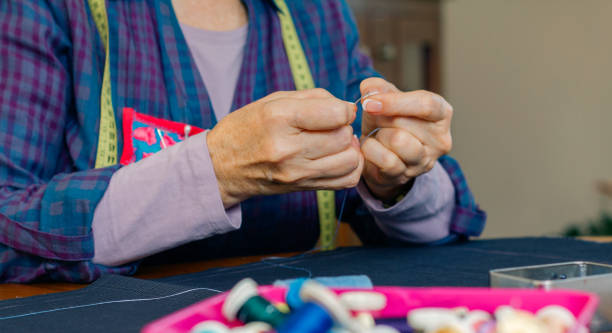 istock Senior female dressmaker threading a needle 1081450846