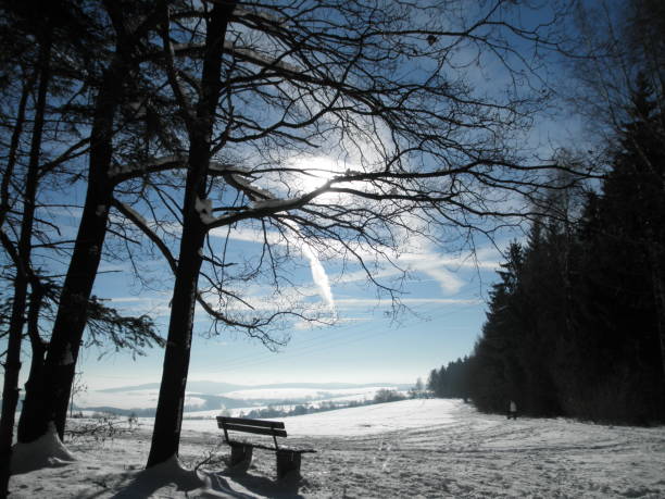 View on the hilly landscape of the Erzgebirge. The Erzgebirge is a German low mountains. Snow-covered landscape and contrails at the blue sky. Good distance vision