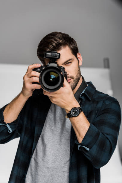 istock handsome young male photographer shooting with professional camera 1081458916