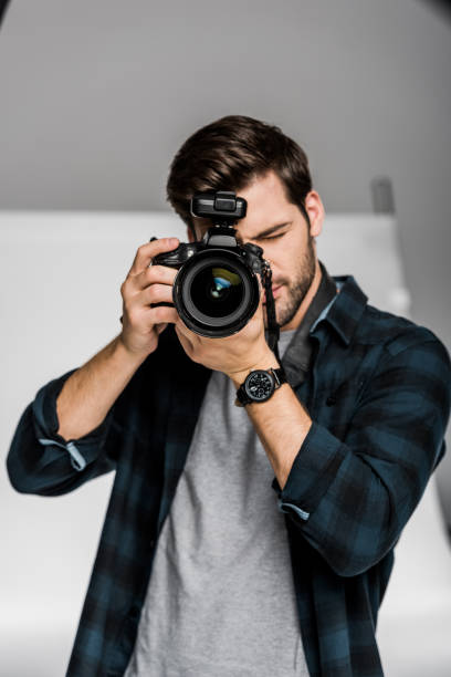 istock handsome young male photographer using professional camera in photo studio 1081458926