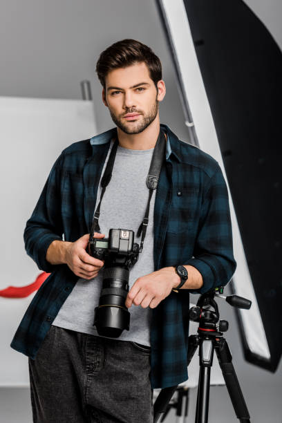 istock handsome professional young photographer looking at camera in photo studio 1081458938