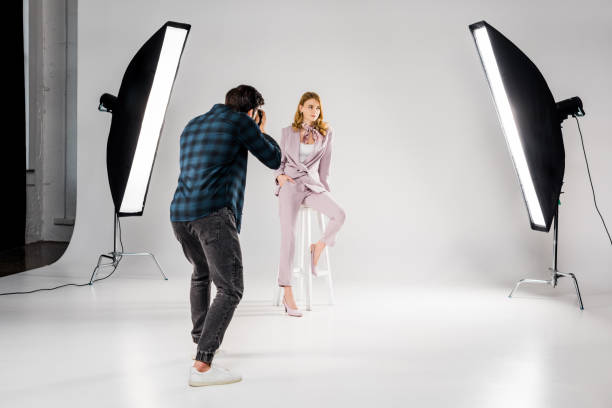 back view of photographer shooting beautiful young female model in photo studio back view of photographer shooting beautiful young female model in photo studio photo studio model stock pictures, royalty-free photos & images