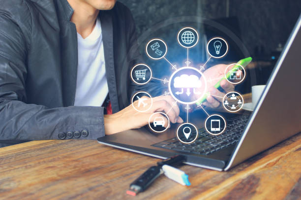 istock Internet of Things (IoT), Business man using laptop computer and hand holding mobile smart phone and iot icon or hologram with in home office, Communication network service and Business concept 1081470938