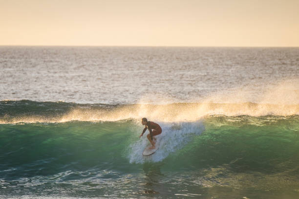 jeune adolescent caucasien apprendre surf sur une grosse houle vague dans l’océan bleu propre au lieu tropical - notion d’activité de l’eau vacances sport pour heureux garçon millénaire - surfing men hawaii islands wave photos et images de collection