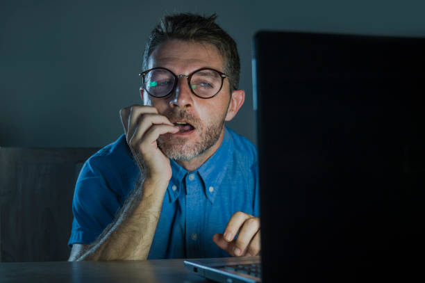 young lascivious and aroused porn addict man in nerd glasses watching sex movie online late night at laptop computer looking pervert and horny in internet pornography and sex content stock photo