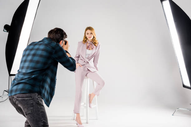back view of photographer shooting beautiful young female model in studio back view of photographer shooting beautiful young female model in studio photo shoot stock pictures, royalty-free photos & images