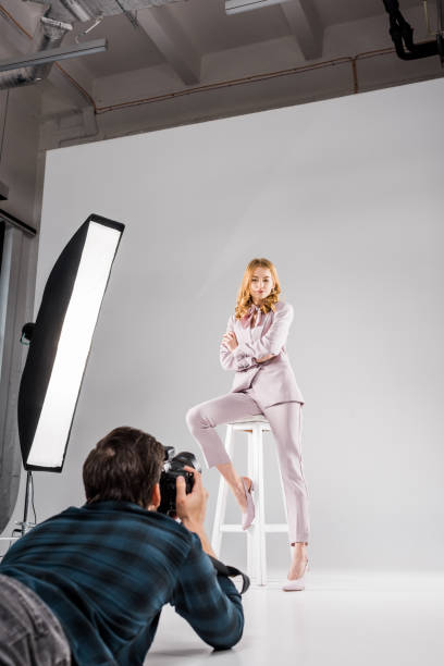 istock photographer with camera lying and photographing beautiful female model posing in studio 1081475954