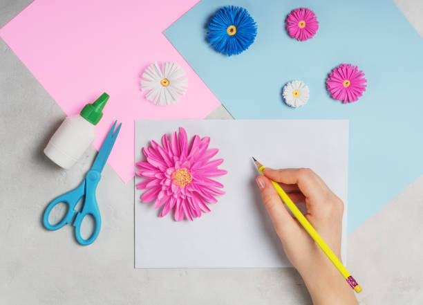 istock Female hands makes greeting card from paper flowers. 1081476518