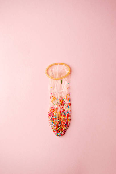 a condom full of nonpareils of many colors on pink background, love saint valentine concept a condom full of nonpareils of many colors on pink background, love saint valentine concept condom photos stock pictures, royalty-free photos & images