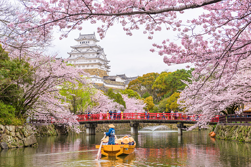 Himeji, Japan - April 9, 2017: Tourists at Himeji Castle take a moat cruise in the spring season. The castle dates from 1333 and is considered one of the finest surviving example of Japanese castle architecture.