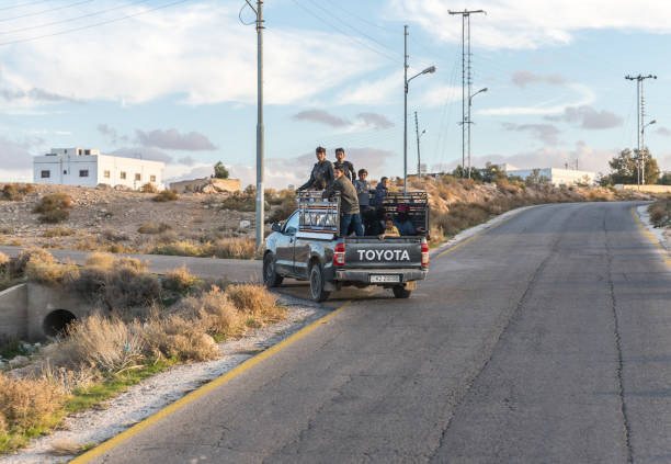 a group of teenagers riding in the open body of the tender on the suburban road near madaba city in jordan - travel jordan israel sand imagens e fotografias de stock
