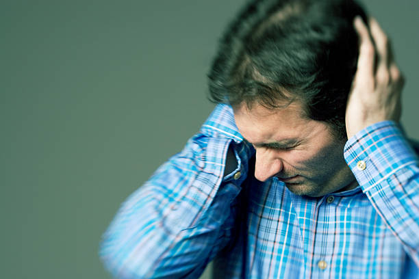 Covering His Ears A color toned image of a man with his hands over his ears trying to block out someone talking.  Blur effect with lensbaby. hands covering ears stock pictures, royalty-free photos & images