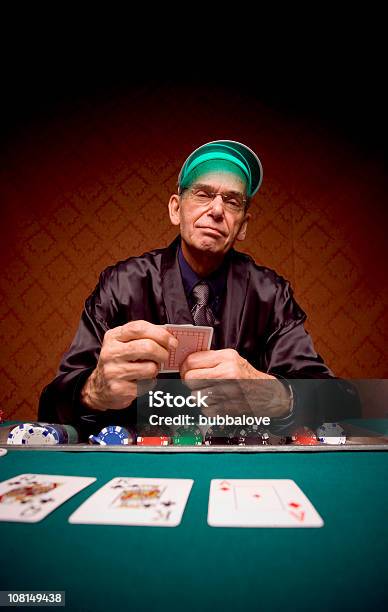 Foto de Sênior Homem Sentado Na Mesa E Jogar Poker Cartão e mais fotos de stock de Aposta - Aposta, Paletó de Smoking, Sério