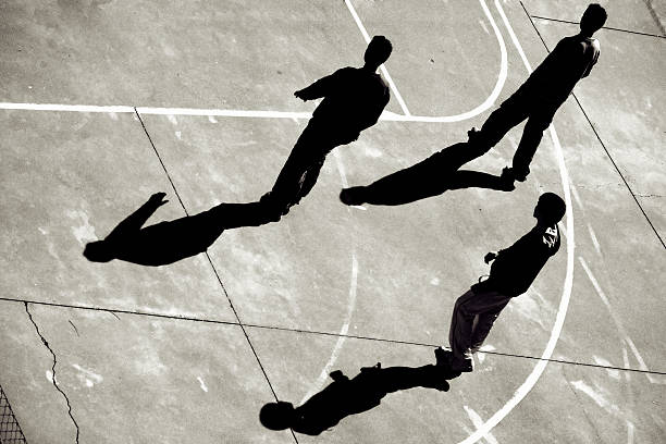 tre ragazzi adolescenti cammina attraverso il campo da basket - three boys foto e immagini stock