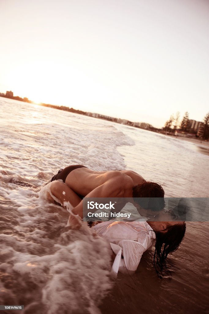 Pareja joven beso en las olas en la playa - Foto de stock de Parejas libre de derechos