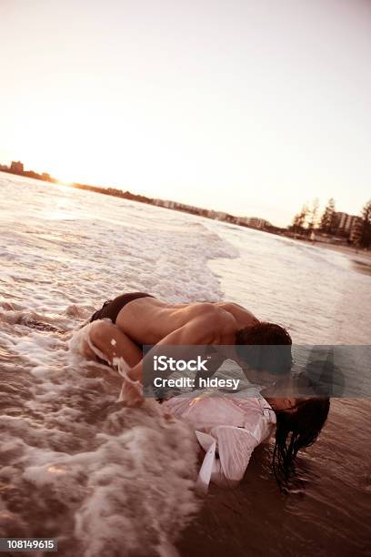 Pareja Joven Beso En Las Olas En La Playa Foto de stock y más banco de imágenes de Parejas - Parejas, Playa, Sensualidad