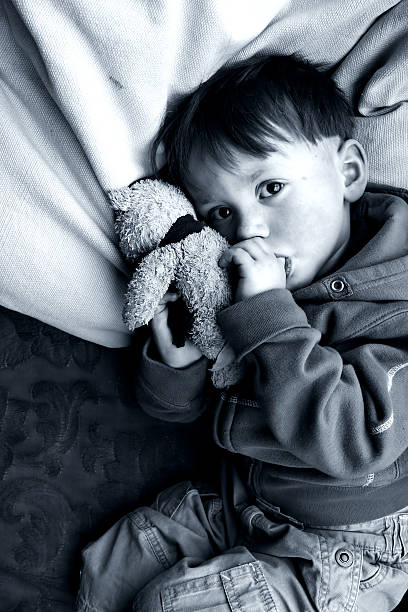istock Little Boy Sucking on Thumb and Holding Teddy Bear 108149668
