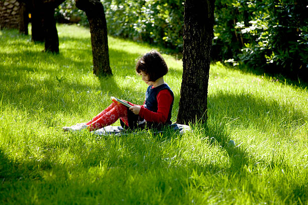 istock Little Girl Reading Book Under Tree 108149961