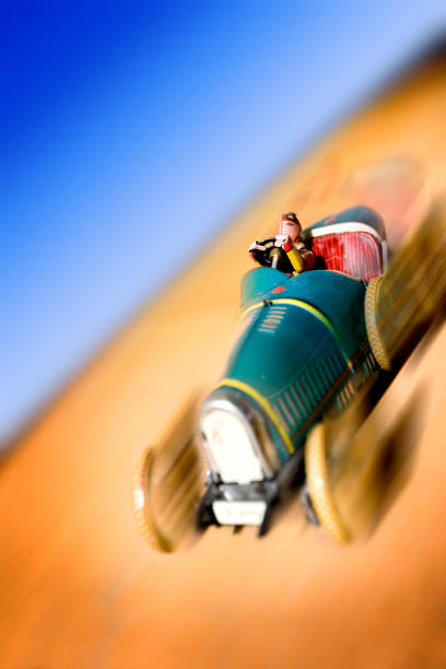 A yellow toy car sits partially sheltered under a red umbrella, symbolizing car insurance protection.