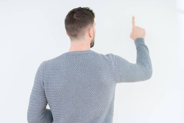 istock Young handsome man wearing casual sweater over isolated background Posing backwards pointing behind with finger hand 1081501284