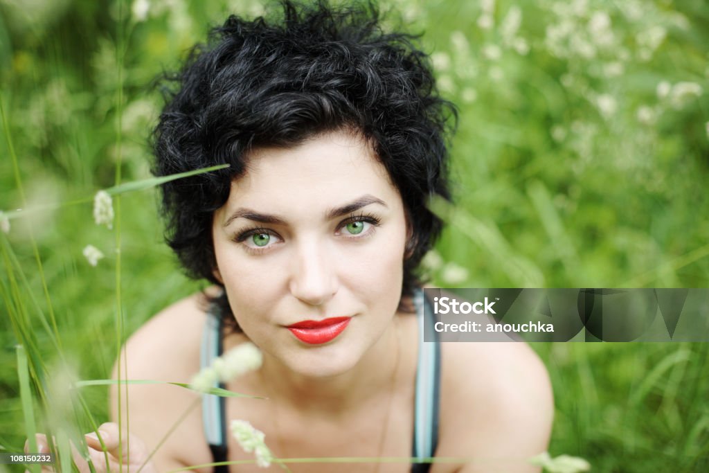 Retrato de jovem mulher sentada na grama - Foto de stock de Olhos Verdes royalty-free