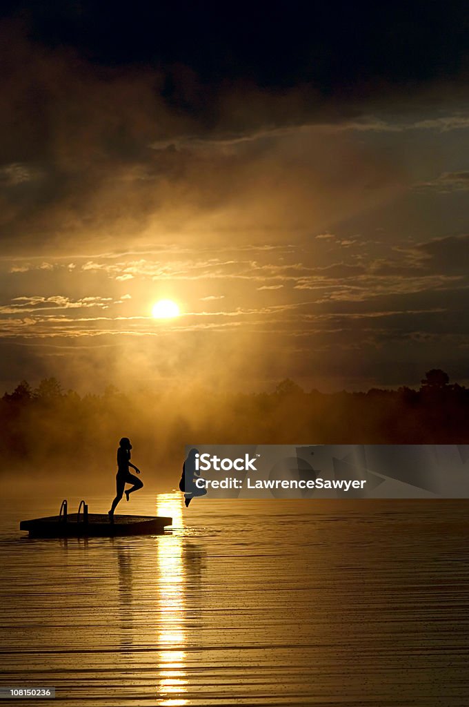 Silueta de Poeple salto en el muelle al atardecer - Foto de stock de Saltar - Actividad física libre de derechos