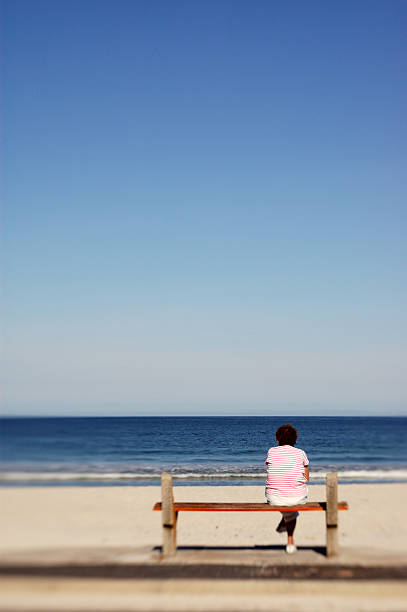 istock Woman Sitting on Bench at Beach 108150309