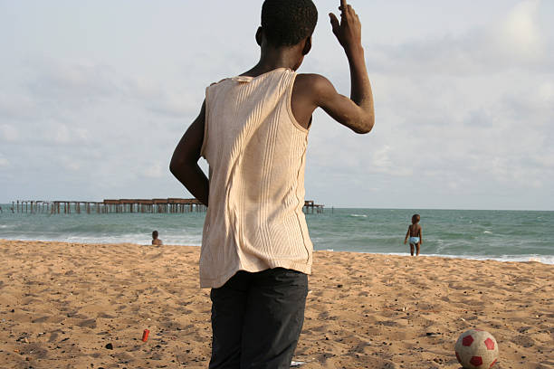Happy colored boy and African American boy playing yellow toy airplane and running by wearing yellow sweater. Having fun on beach after unlock down city from COVID19. concept of dreams and travels