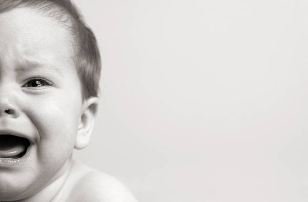 Half of Newborn Baby's Face Crying, Isolated on Gray