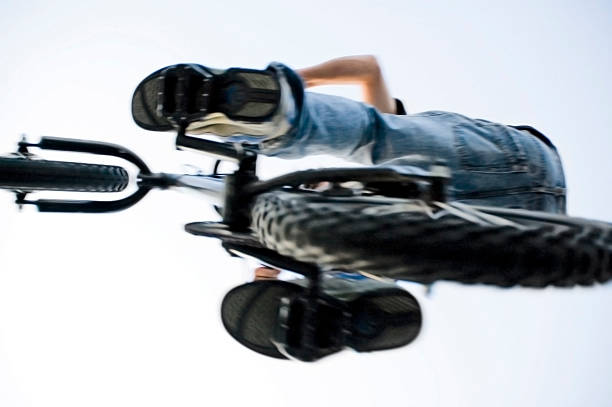 Freestyle cyclist practicing street BMX in backlight at sunset