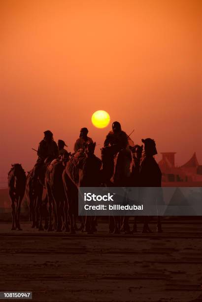 Foto de Caravana De Pessoas Viajando Em Camelos No Pôrdosol e mais fotos de stock de A caminho