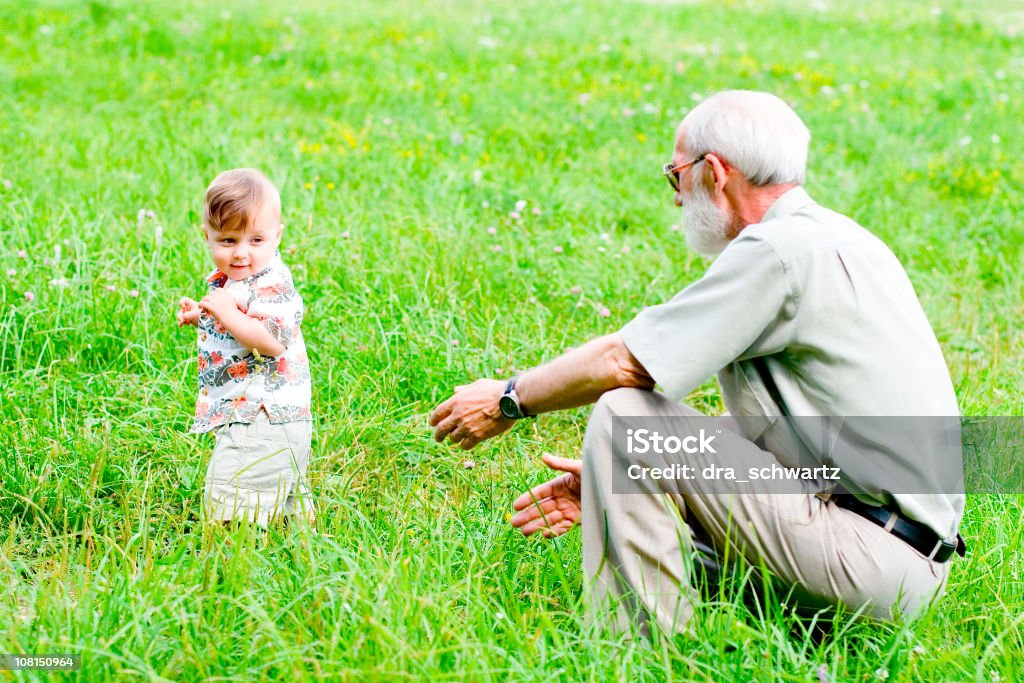 Grand-père jouant avec bébé à l'extérieur dans le parc - Photo de Accroupi libre de droits