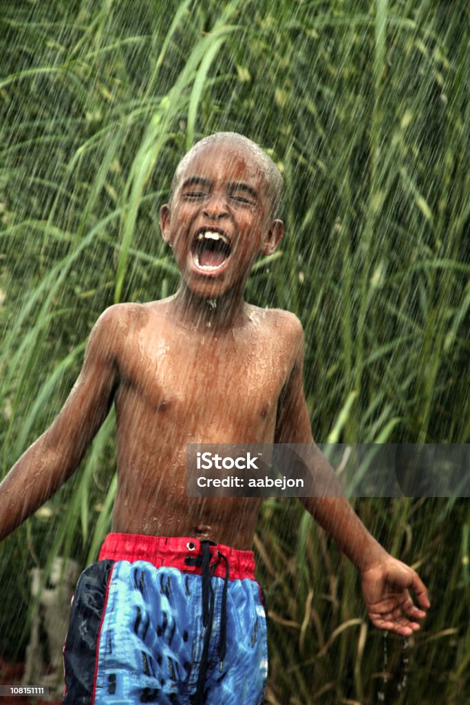 Felice piccolo ragazzo di indossare costume da bagno giocando con la pioggia - Foto stock royalty-free di Bambino