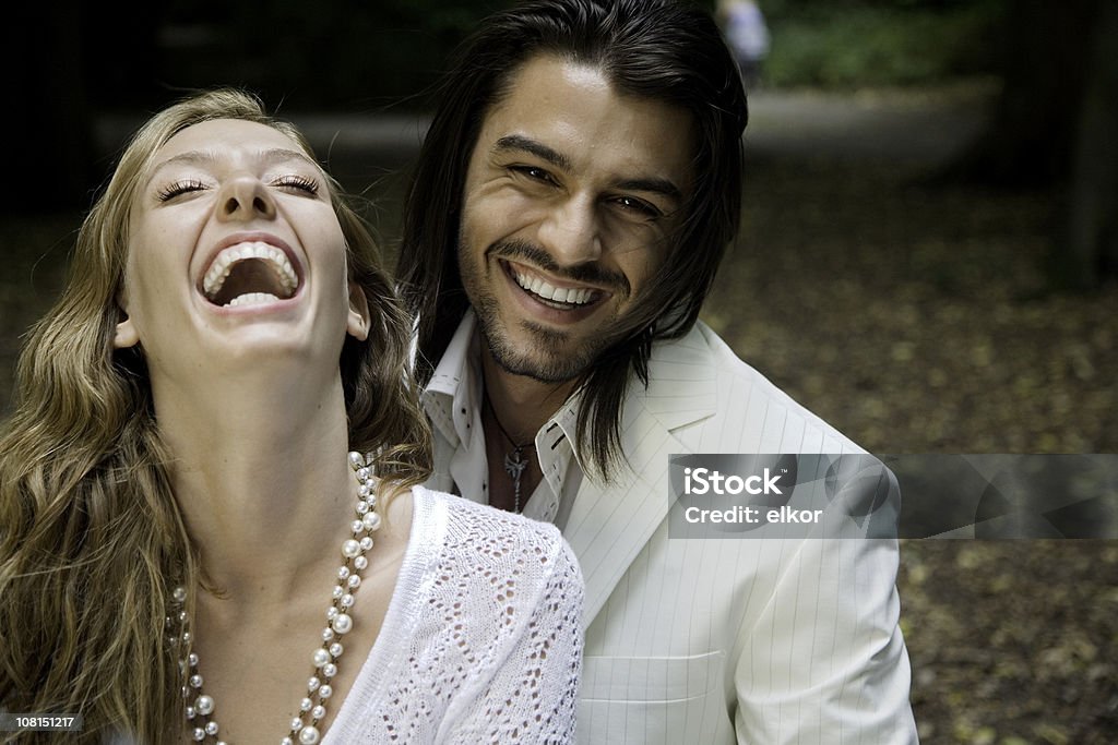 Ritratto di giovane coppia ridendo nel parco - Foto stock royalty-free di Abbigliamento casual