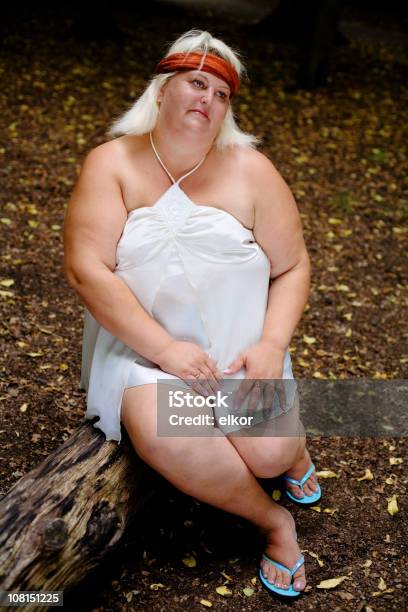 Portrait Of Overweight Woman Sitting On Log In Forest Stock Photo - Download Image Now