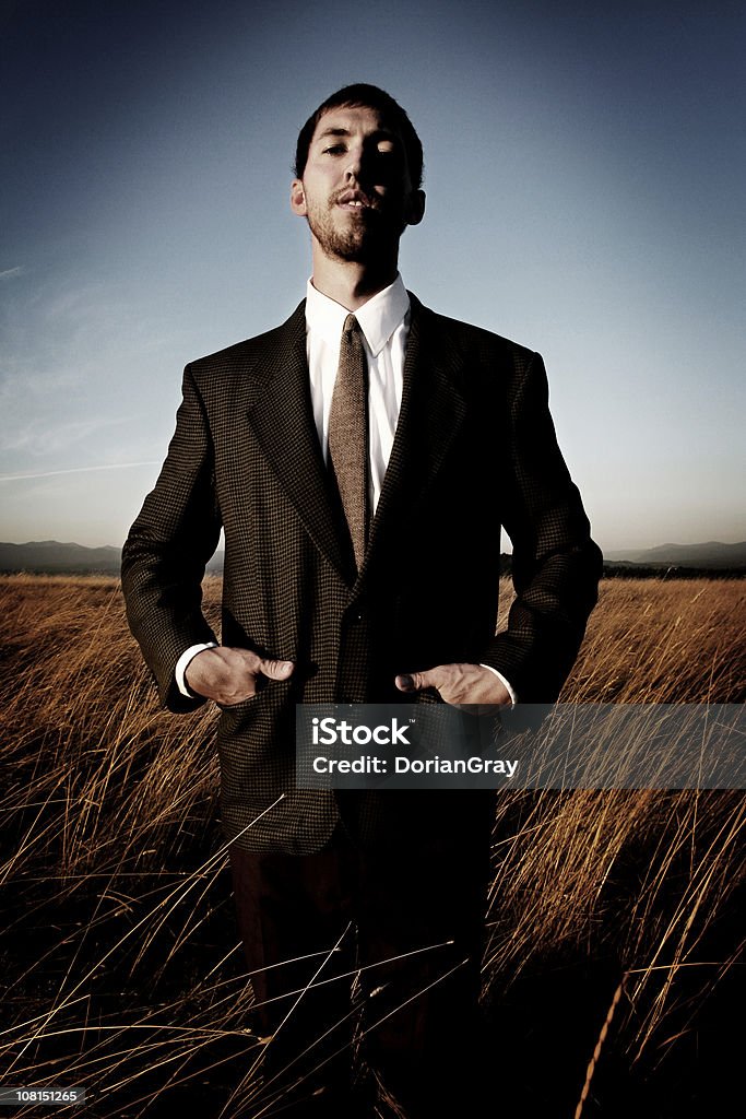 Homme d'affaires avec les mains dans les poches debout dans le champ de la ferme - Photo de Champ libre de droits
