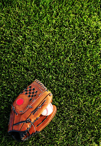 3d rendering of orange baseball glove with a baseball suspended in air above wooden surface near blue wall with copy space. Hobbies and leisure. Active games. American sports.