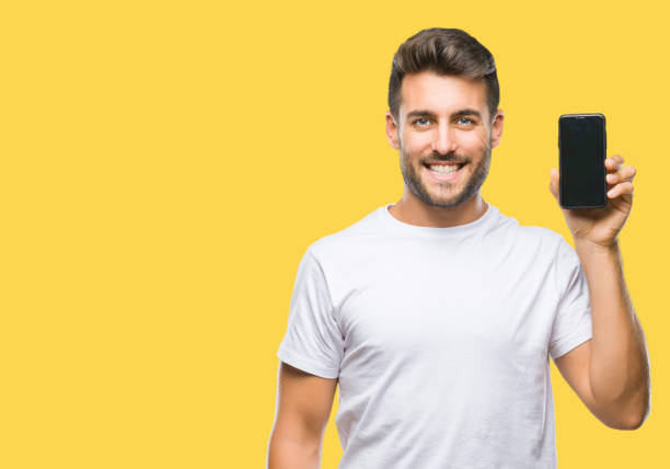 istock Young handsome man showing smartphone screen over isolated background with a happy face standing and smiling with a confident smile showing teeth 1081515514