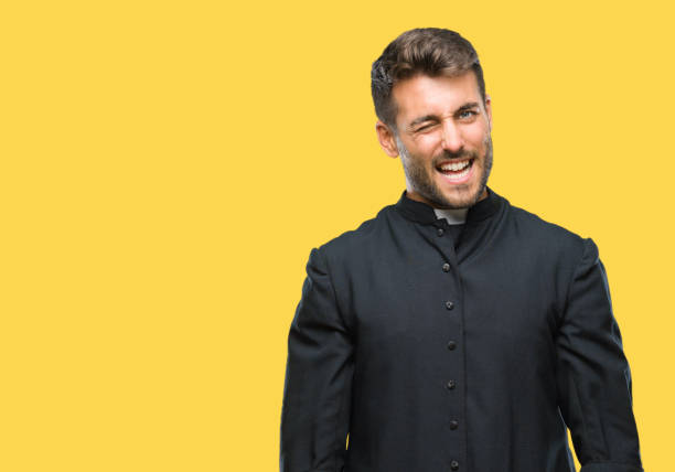 istock Young catholic christian priest man over isolated background winking looking at the camera with sexy expression, cheerful and happy face. 1081515676