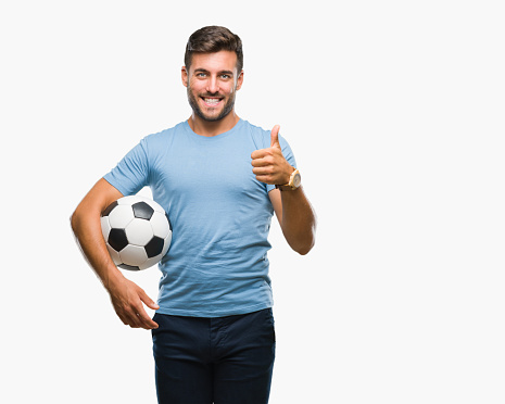 Young handsome man holding soccer football ball over isolated background happy with big smile doing ok sign, thumb up with fingers, excellent sign