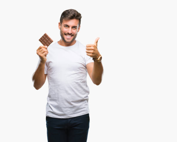 istock Young handsome man eating chocolate bar over isolated background happy with big smile doing ok sign, thumb up with fingers, excellent sign 1081517220