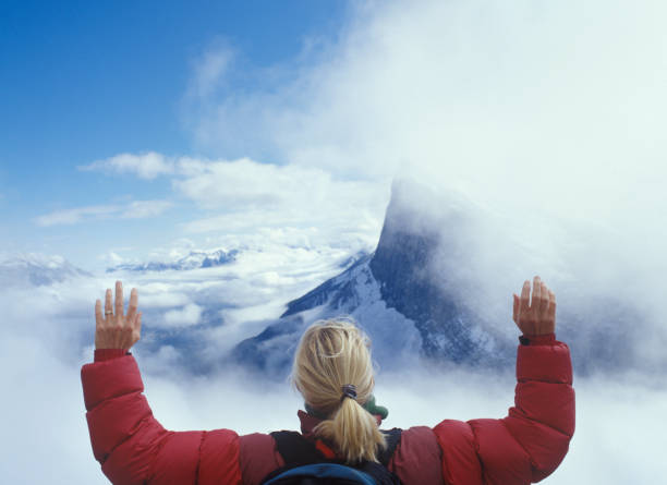She looks off to distant scene of mountain peak and sky