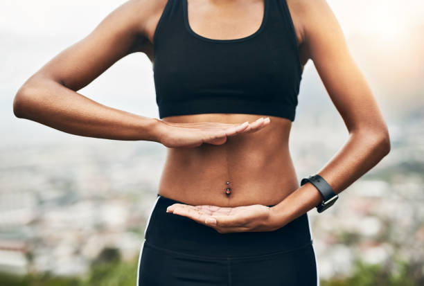 Keeping her core strong Closeup shot of a sporty unrecognizable woman holding her hands against her stomach outside sports bra stock pictures, royalty-free photos & images