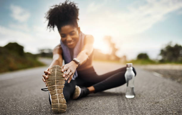 Getting through her warmup routine Shot of a sporty young woman stretching her legs while exercising outdoors touching toes stock pictures, royalty-free photos & images
